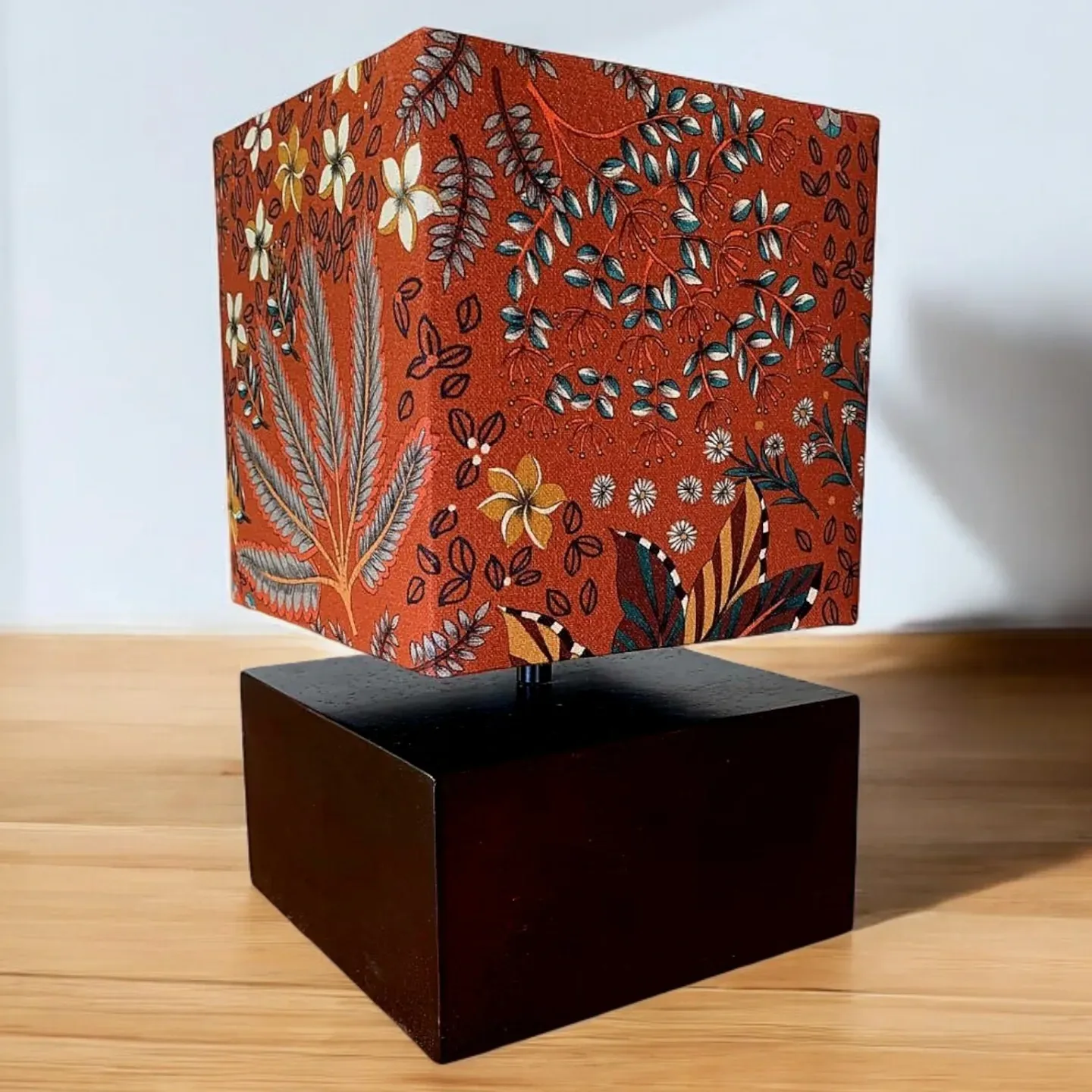 Abat-jour carré en tissu indien terracotta à fleurs sur un socle cubique en bois foncé