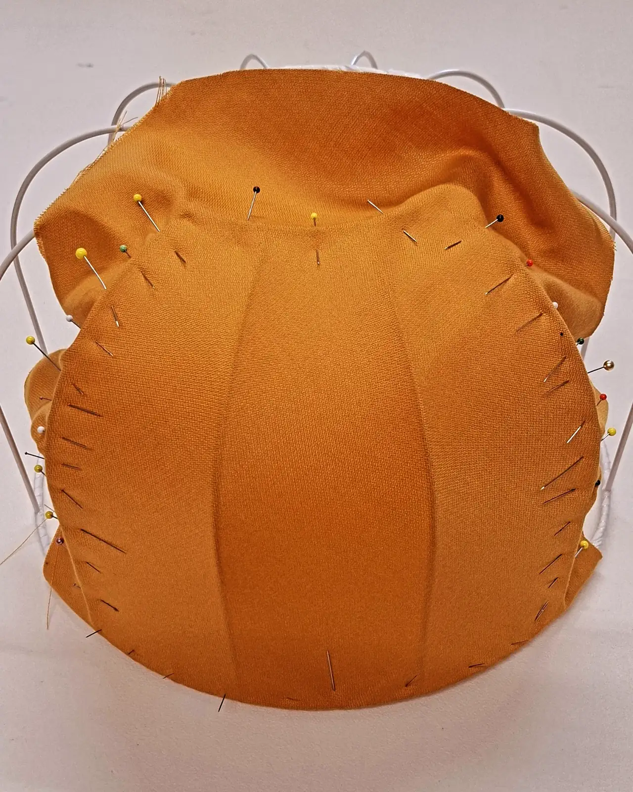 Tissu ocre épinglé sur une carcasse d'abat-jour en cours de fabrication