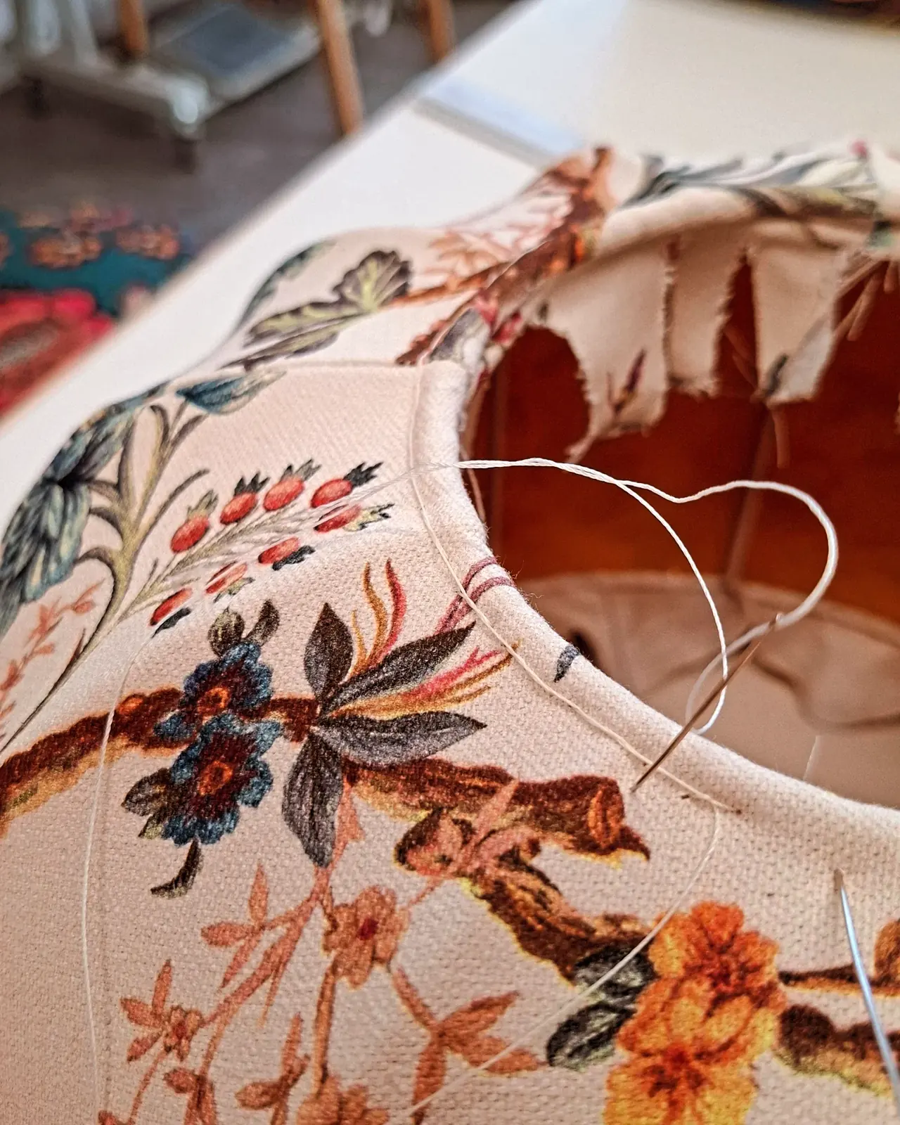 Gros plan sur la couture à la main d'un abat-jour fleuri sur sa carcasse métallique