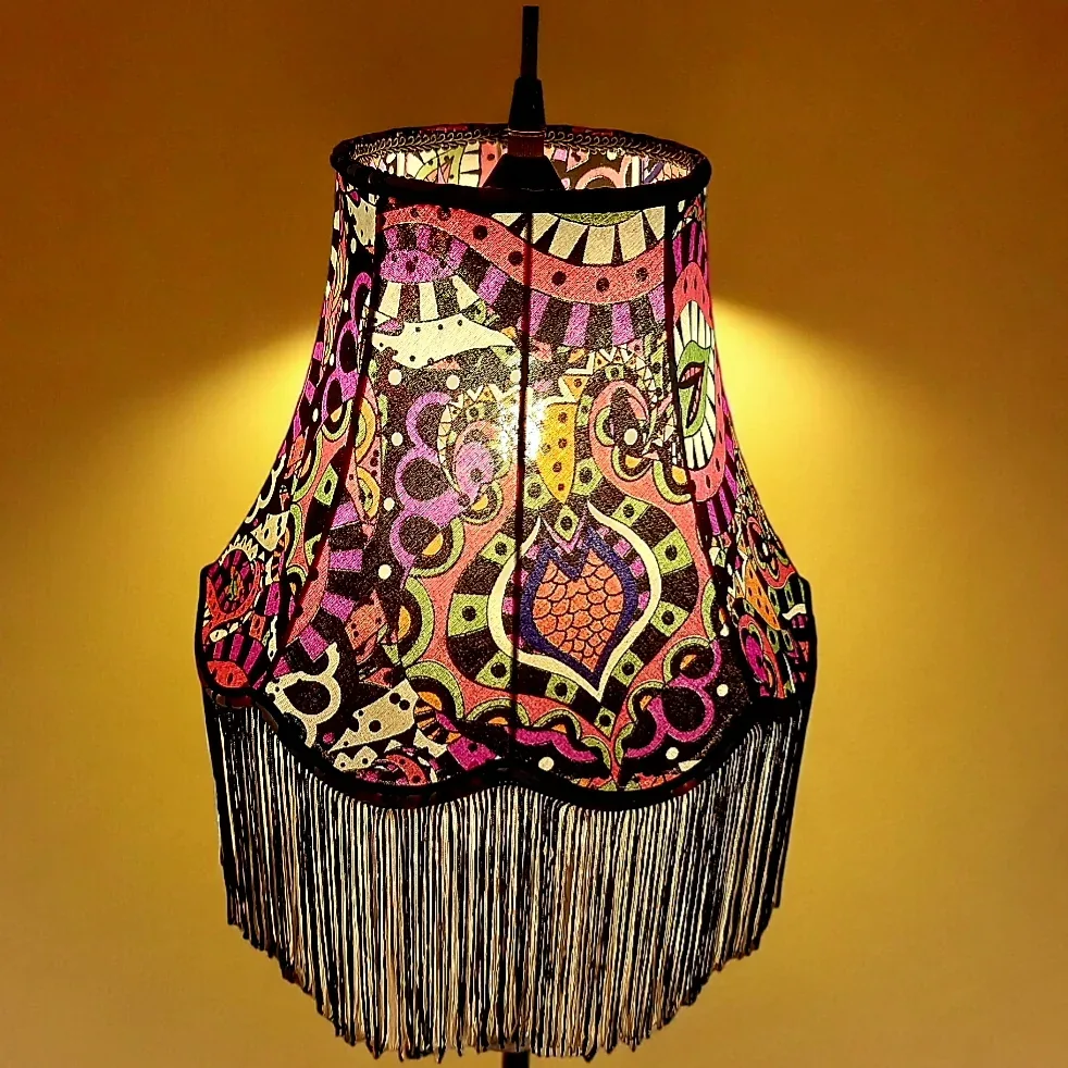 Suspension pagode en tissu psychédélique rose, vert et violet avec longues franges noires, sur fond jaune