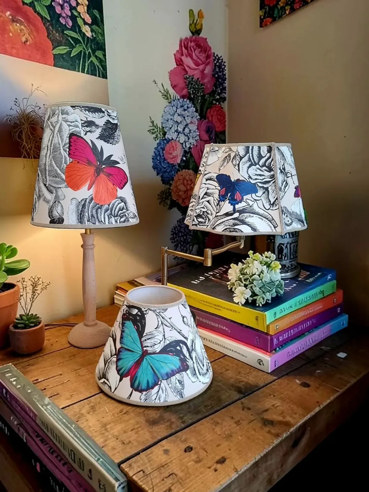 Trois abat-jour réalisés dans le papier peint Butterfly d'Osborne & Little, posés sur des piles de livres
