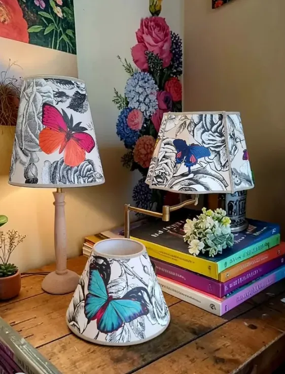 Trois abat-jour à motifs papillons sur pieds de lampe en bois et laiton