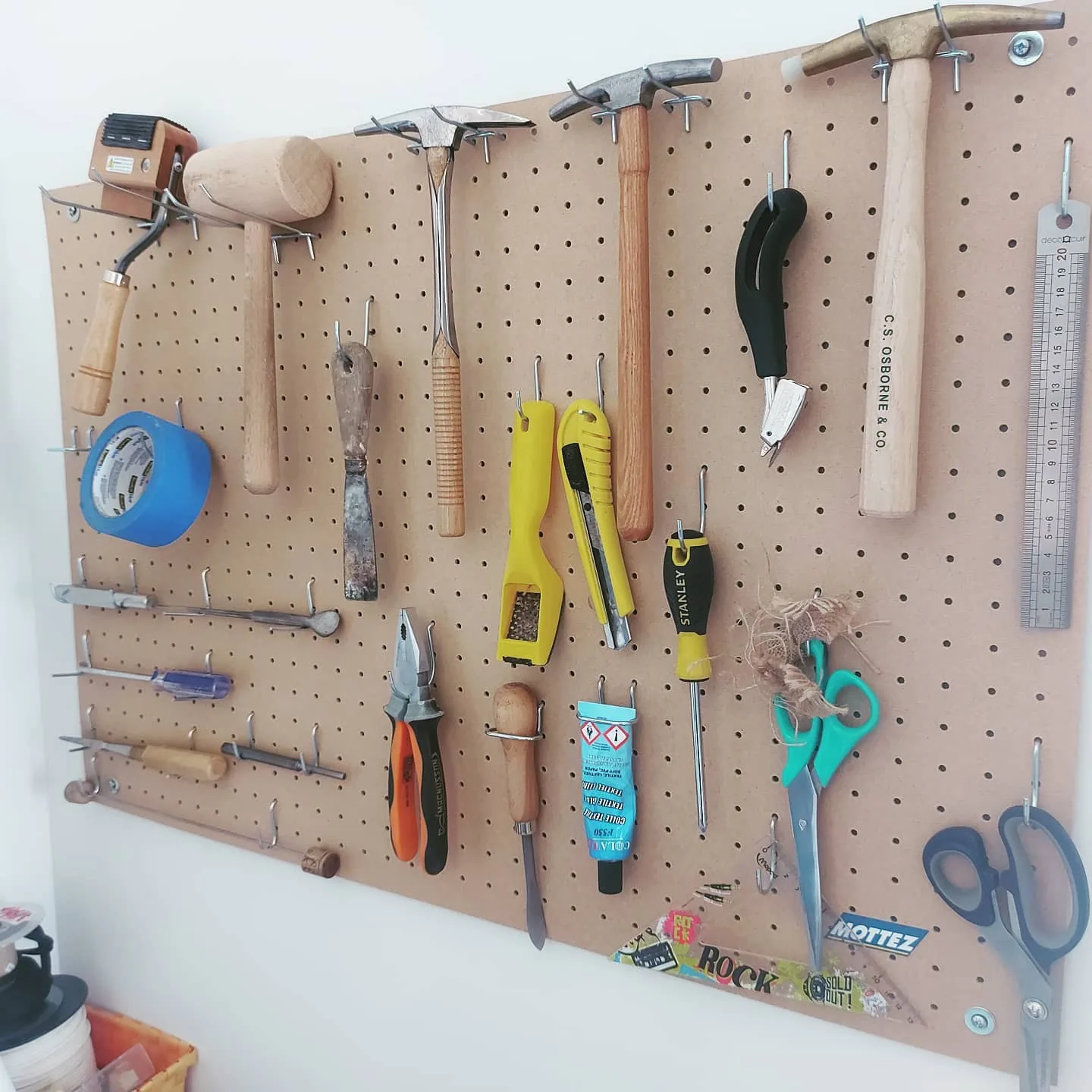 Panneau perforé de l'atelier avec les outils du tapissier : marteaux, ciseaux, pinces, ficelle