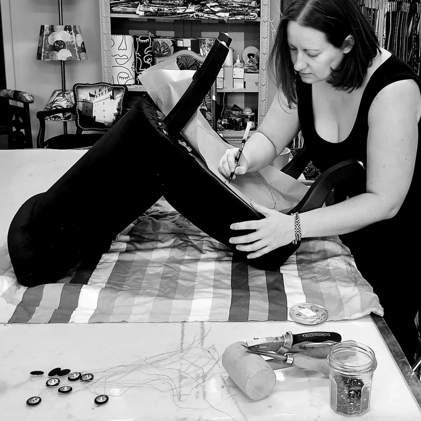 Séverine Templier traçant un gabarit sur une assise noire dans son atelier, photo en noir et blanc