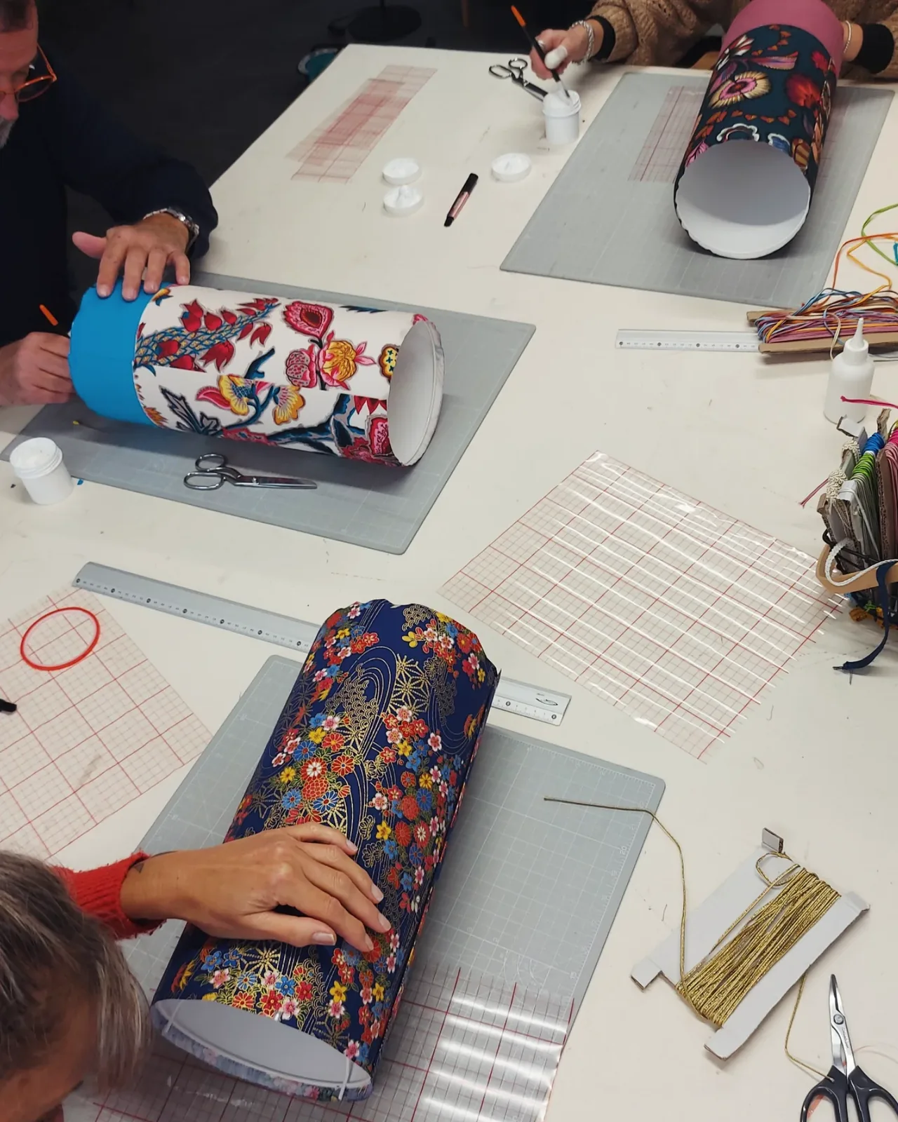 Tables de l'atelier pendant un stage, tambours d'abat-jour fleuris en cours de collage