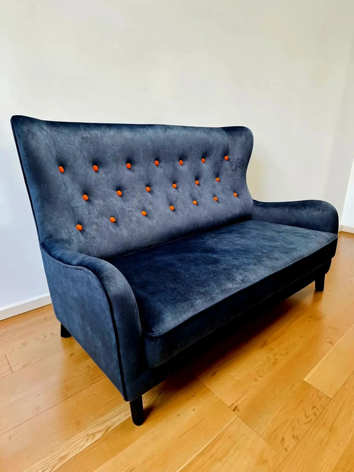 Canapé rétro capitonné retapissé en velours bleu profond avec boutons orange, sur parquet clair
