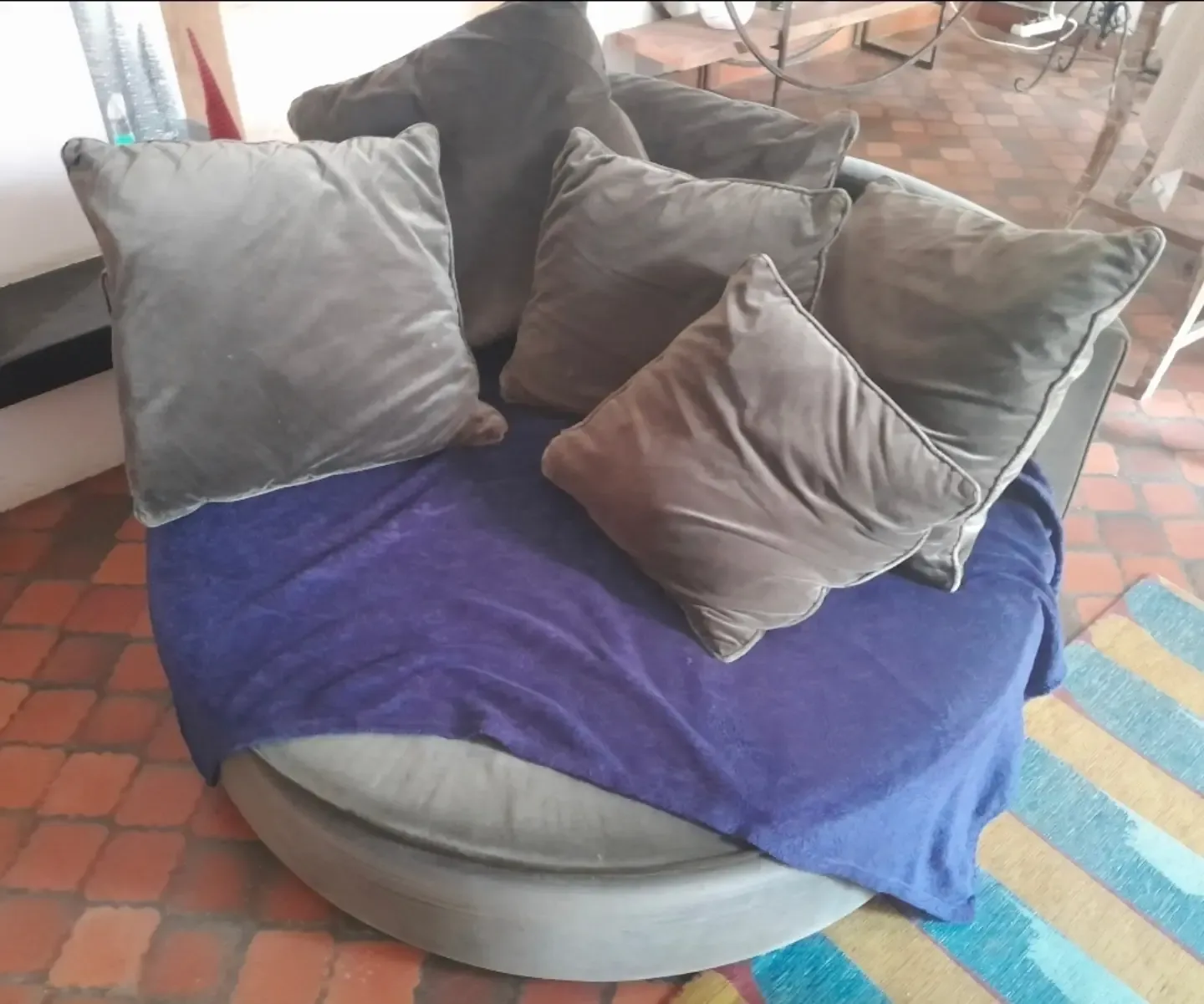 Canapé rond gris fatigué couvert d’un plaid violet, avant réfection
