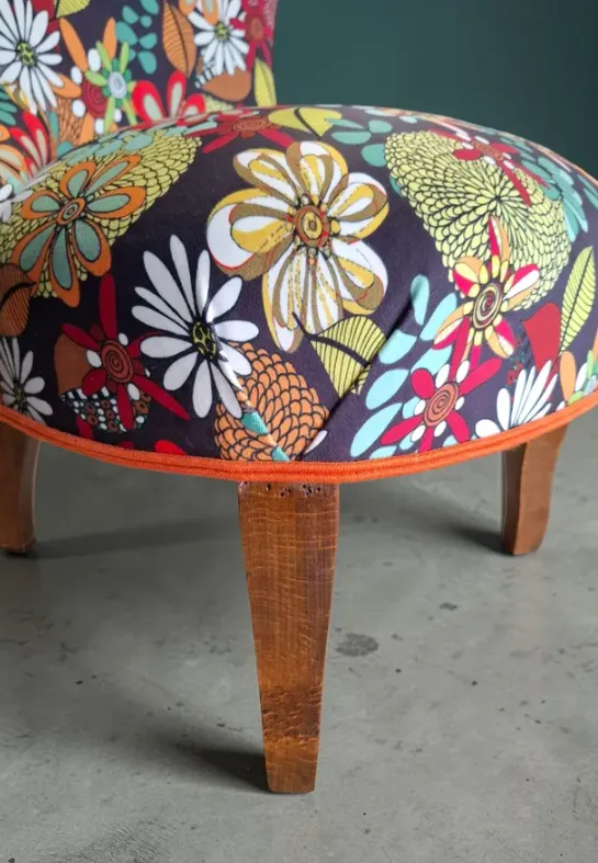Chauffeuse retapissée d'un tissu fleuri multicolore sur pied en bois