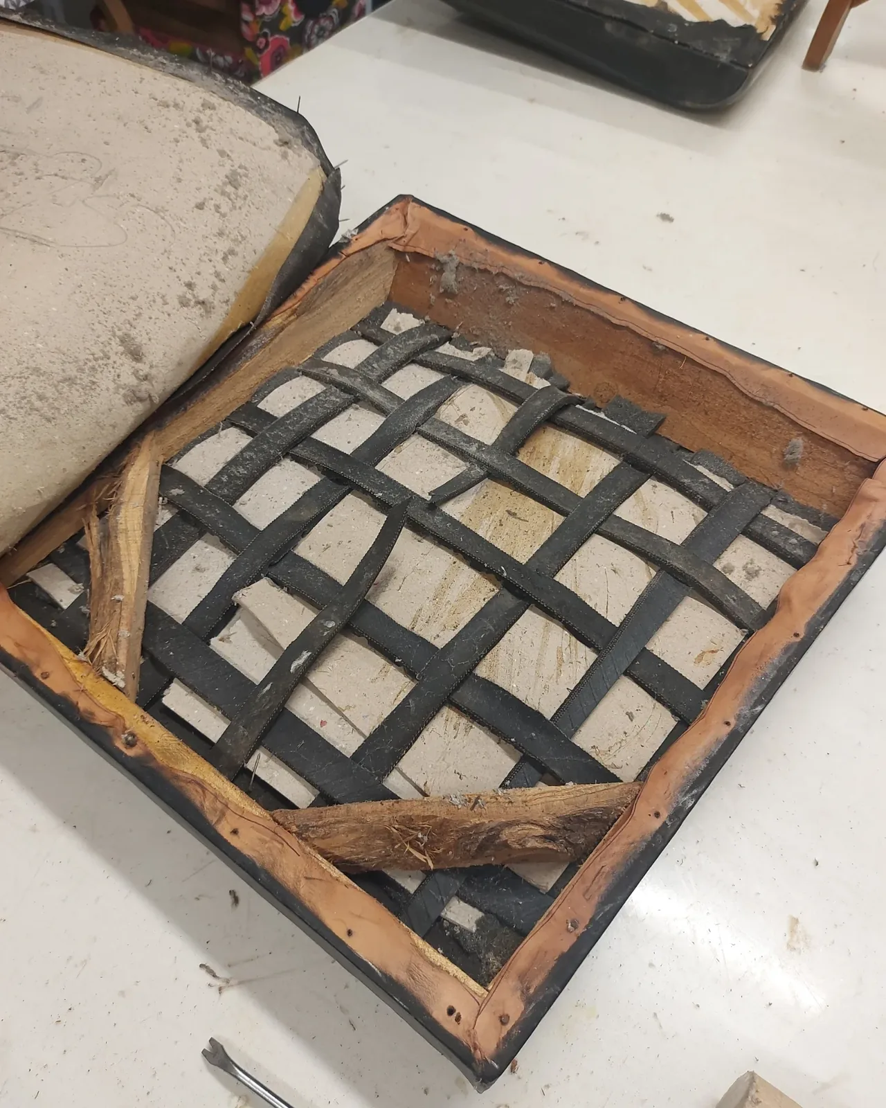 Assise d'un fauteuil dégarnie jusqu'au bois, anciennes sangles de jute noircies visibles
