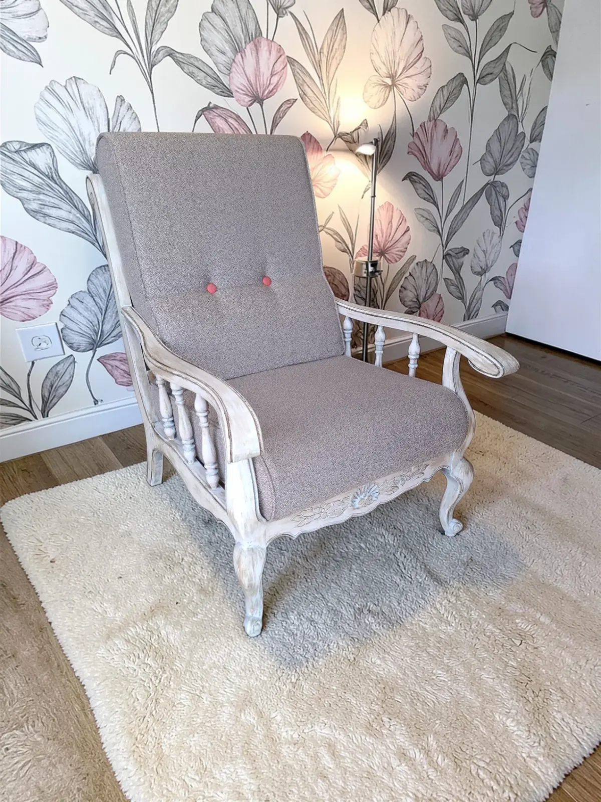 Fauteuil vintage en bois patiné blanc avec housses neuves en tissu gris Chill de JAB, devant un papier peint fleuri