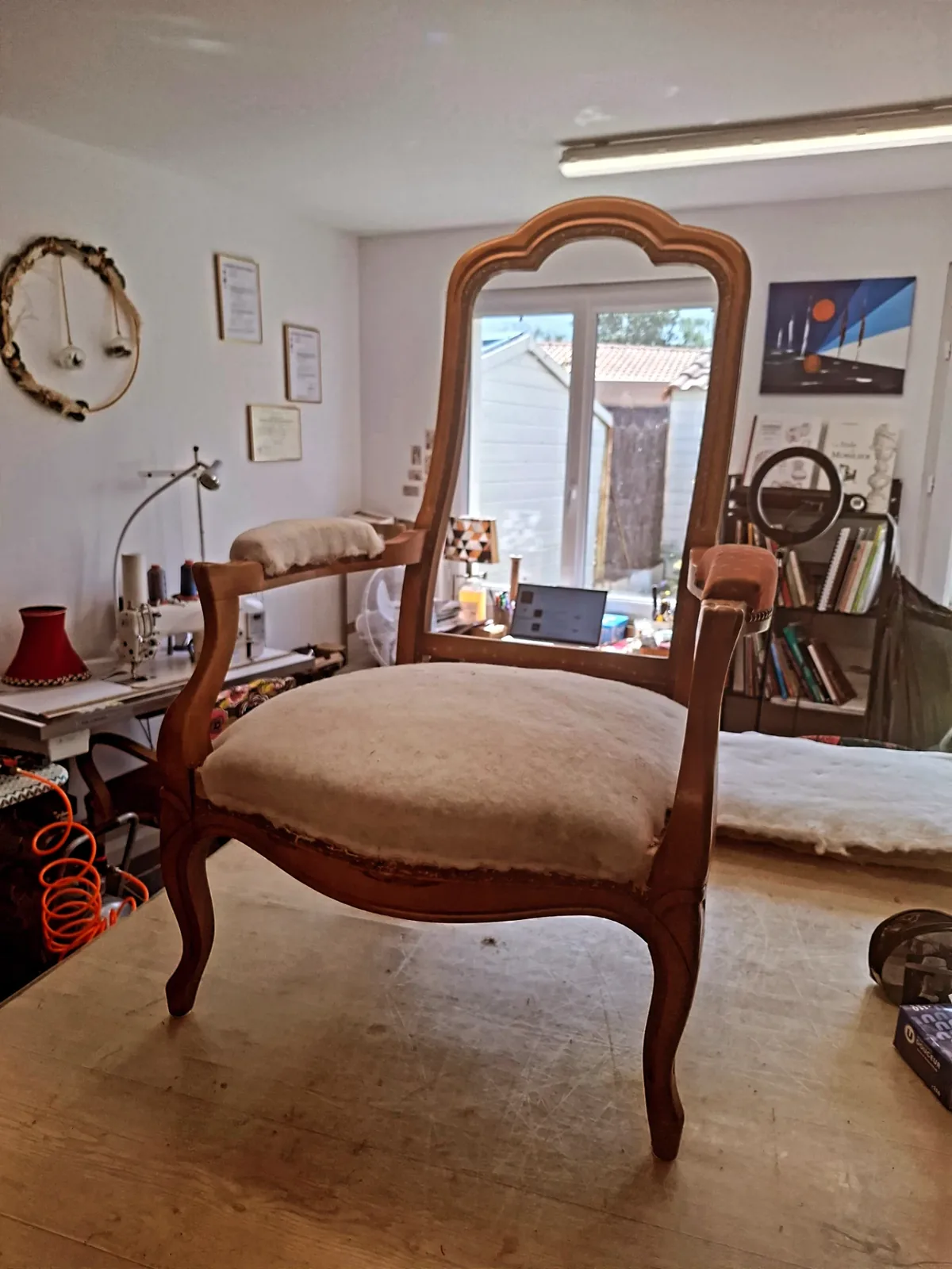 Fauteuil Voltaire au tissu beige usé, photographié dans un salon avant réfection