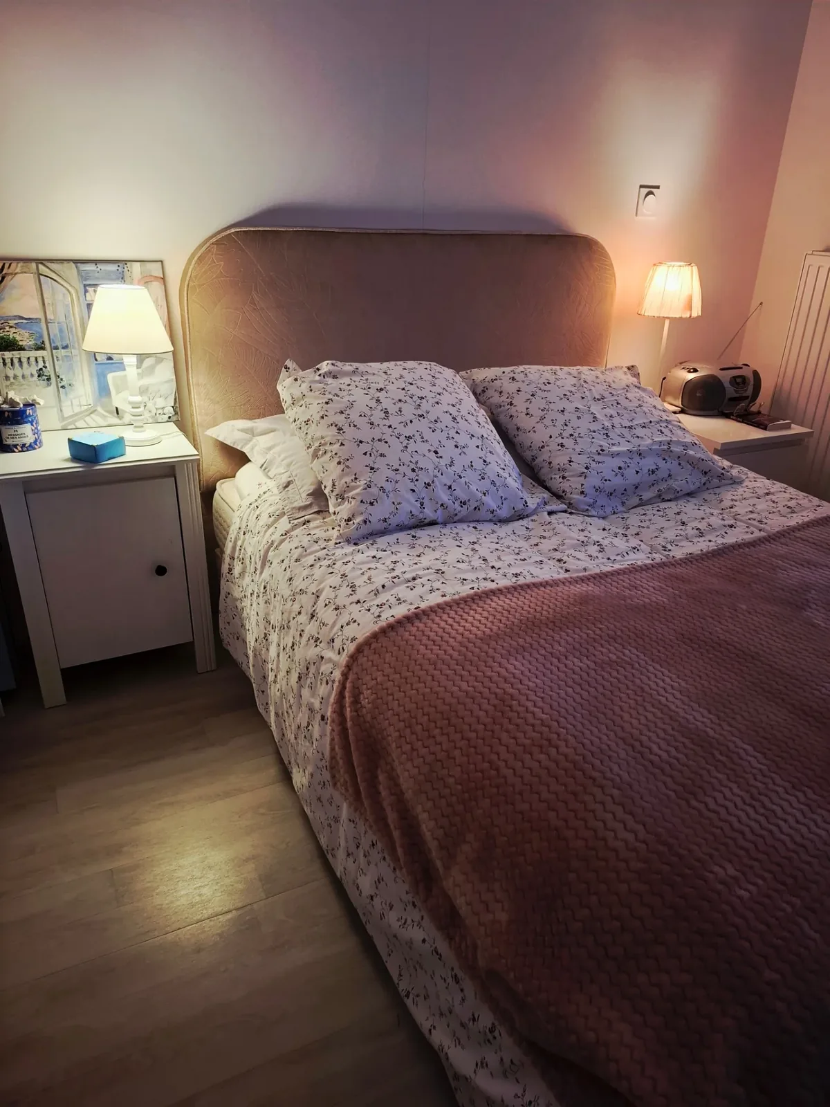 Tête de lit arrondie en velours rose poudré Camengo dans une chambre, lampes de chevet allumées